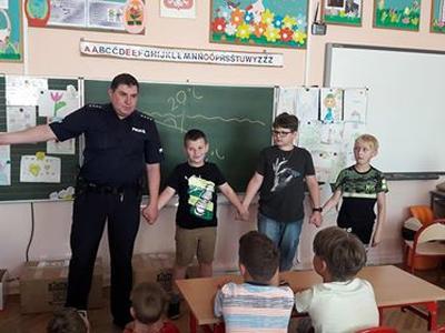 Policjant i trójka dzieci trzymających się za ręce.