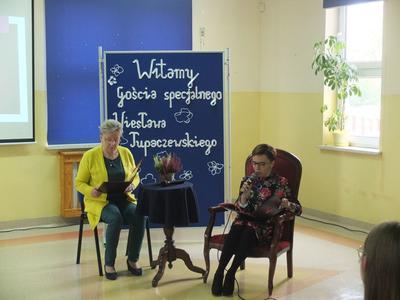 Dyrektor szkoły Żaneta Wesołowska siedzi i czyta książkę do mikrofonu