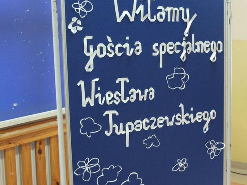 Tablica z białym napisem Witamy Gościa specjalnego Wiesława Tupaczewskiego.