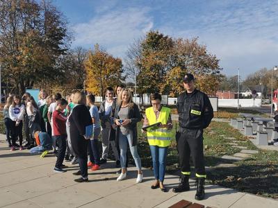 Grupa osób wraz ze strażakiem stojąca na dworze.