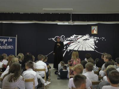 Ksiądz przemawiający do uczniów.