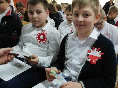 Dwóch siedzących uczniów w białych koszulach.