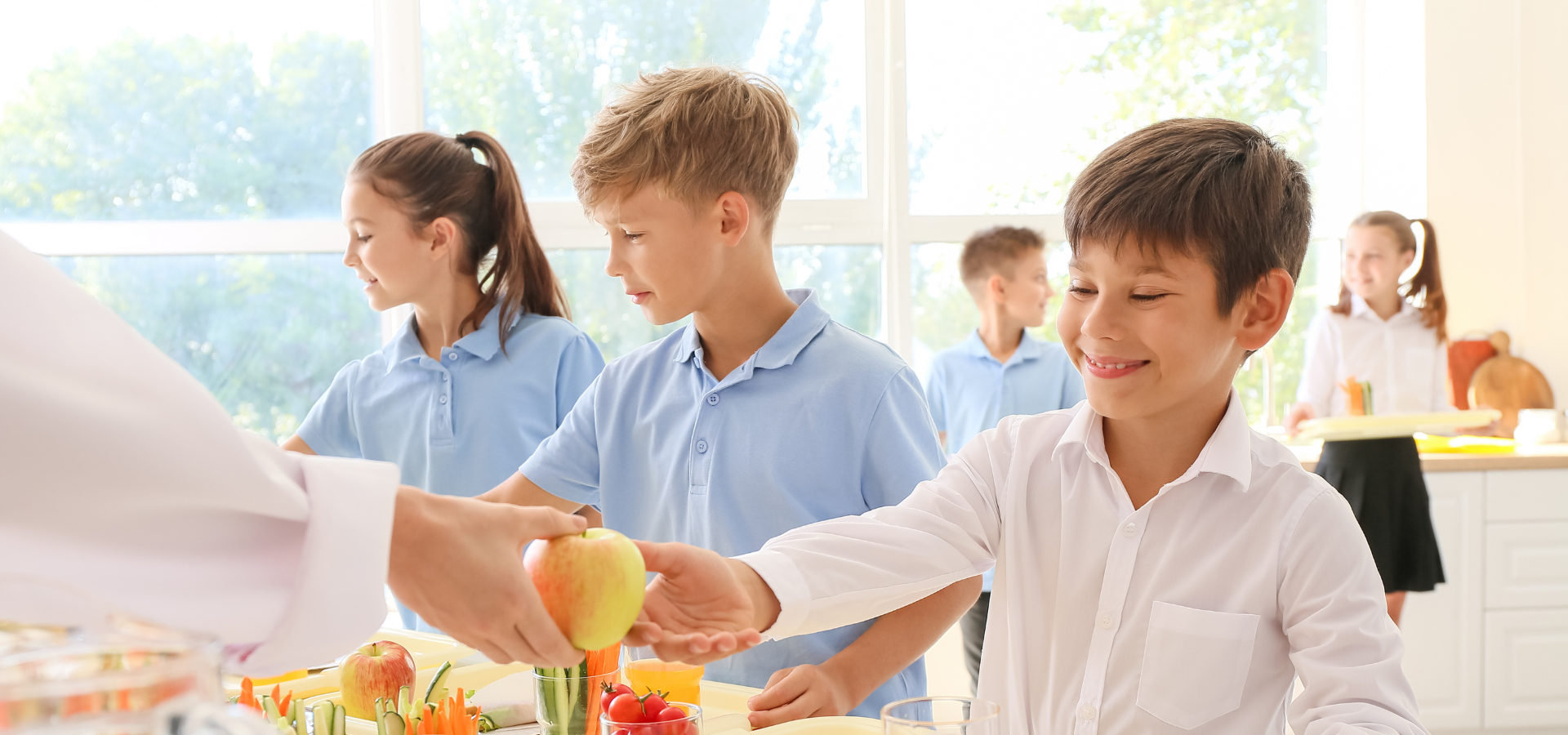 Zdjęcie dzieci. Chłopiec dostaje do ręki jabłko.