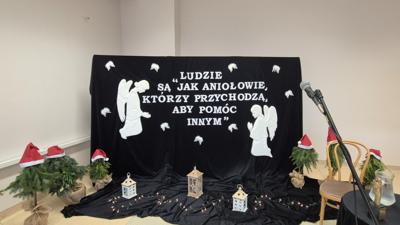 Wystroj sali plansza ludzie sa jak aniołowie, którzy przychodzą aby pomóc innym