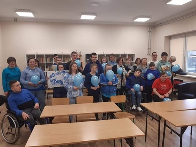 Uczniowie PDP,  ubrani na niebiesko, trzymają niebieskie balony oraz plakat tematyczny.