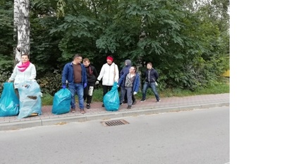 Nauczyciele wraz z uczniami wracają ze skończonej akcji. Trzymają w rękach worki z zebranymi śmieciami.