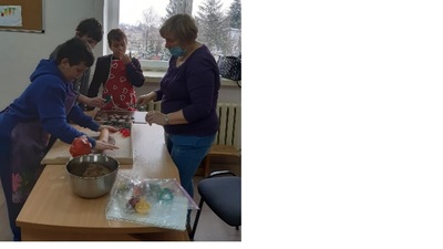 Pani Wiesia i trzech chłopców wałkuje ciasto i wykrawa pierniczki.