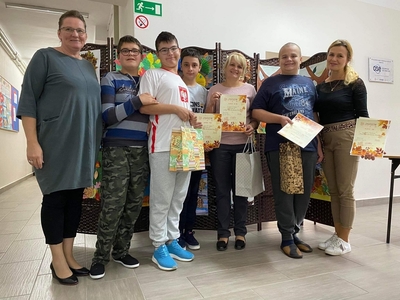 Laureaci konkursu wraz z panią Dyrektor pozują do zdjęcia na tle wystawy prac.