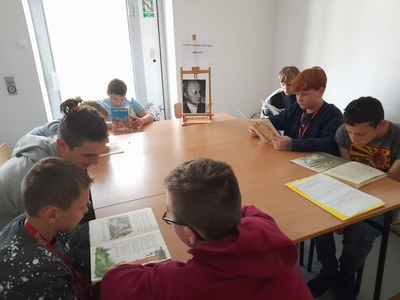 Na zdjęciu chłopcy, czytają utwory Janiny Porazińskiej. Na stole stoi portret autorki czytanych książek.