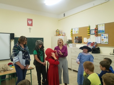 Zdjęcie przedstawia inscenizację bajki pt. „Czerwony kapturek”. Na zdjęciu Pani Beata prowadząca warsztaty, uczennica przebrana za Czerwonego Kapturka, uczeń za wilka, dziewczynka za mamę oraz Pani Aneta przebrana za babcię.