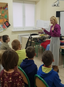 Na zdjęciu Pani prowadząca warsztaty czyta książkę. Uczniowie aktywnie słuchają czytanej bajki.