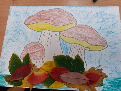 Praca plastyczna przedstawiająca grzyby. Wykonana kredkami oraz wyklejona liśćmi.