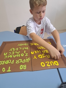 Kacper wykonuje plakat, przykleja litery.