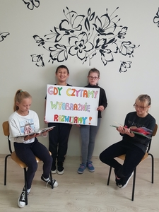 Klasa pani Oli trzyma plakat z napisem "Gdy czytamy, wyobraźnię rozwijamy"