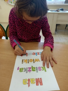 Madzia koloruje hasło „Mała książka, wielki człowiek”.