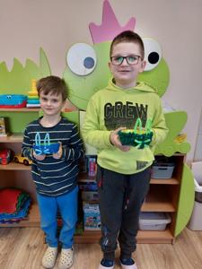 Chłopcy prezentują wykonane miseczki dla kotka.