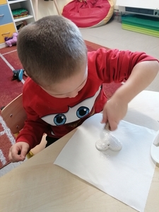 Hubert ozdabiają brokatem serduszko na choinkę. 