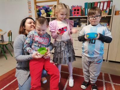 Pani Basia ze swoim oddziałem prezentuja wykonane miseczki dla kotka. Wszyscy są uśmiechnięci.