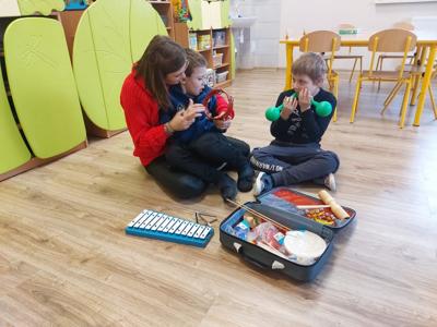 Na zdjęciu Pani Marta z dziećmi a obok walizka z instrumentami.