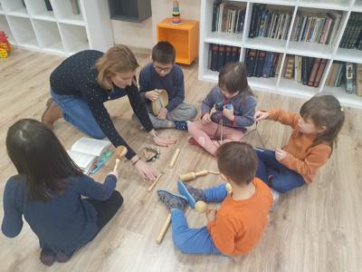 Na zdjęciu oddział przedszkolny z wychowawczynią. Wszyscy siedzą w kole a w środku koła Pani
Ania prezentuje dzieciom instrumenty muzyczne.