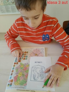 Na zdjęciu Krystian, uczeń klasy 3 aut. Chłopiec odszukuje herb miasta Lublin i koloruje go według wzoru.