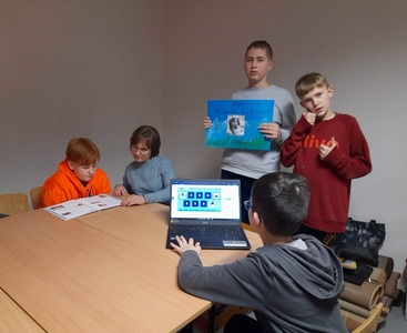 Na zdjęciu Pani Aneta i Michał czytają ciekawostki na temat Wandy Rutkiewicz. Alan i Jakub prezentują plakat a Franek wykonuje ćwiczenie interaktywne na komputerze