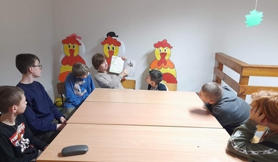 Uczniowie siedzą przy stole. Pani Aneta pokazuje dzieciom fotografię przedstawiającą Jaśka Mela. 