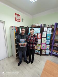 Dominik odbiera dyplom i nagrodę za zajęcie 3 miejsca w konkursie plastycznym. Na zdjęciu z Panią Wicedyrektor a w tle przepiękne prace plastyczne.