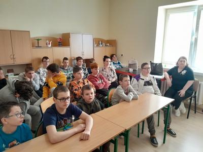 Uczniowie klas szkoły podstawowej wraz z nauczycielami  oglądają film związany Dniem Pamięci Ofiar Zbrodni Katyńskiej.