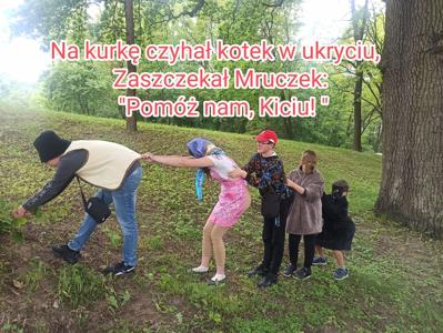 Na zdjęciu dzieci ciągnął rzepkę. Do nich dołącza kotek. 