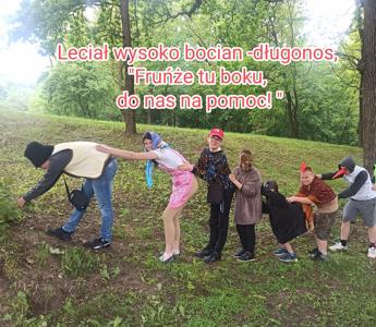 Dzieci przebrane w stroje ciągną rzepkę. Dołącza bocian. Wszyscy są uśmiechnięci