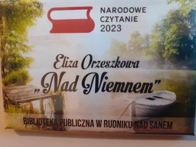 Plakat ukazujący tytuł i autorkę powieści "Nad Niemnem". 