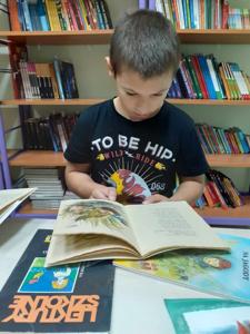 Kuba przygląda się ilustracji zamieszczonej w książce. 