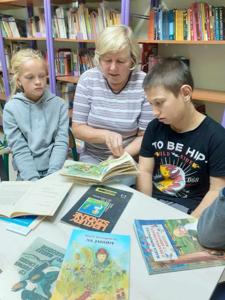 Ola i Kuba z zaciekawieniem słuchają książki czytane przez Panią bibliotekarka. 