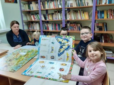 Klasa 1 z wychowawczynią oglądają ciekawe książki w bibliotece szkolnej. 
