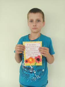  Tadeusz trzyma kartkę, którą zrobił Nauczycielom z okazji ich święta. 