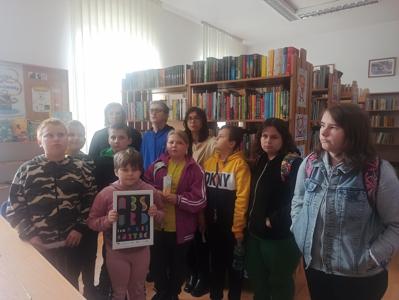 Cała grupa z bibliotekarką. Milenka trzyma hasło przewodnie "Absurd nie czytać"
