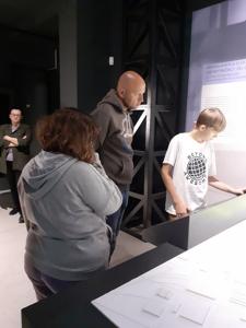 Pan Tomek, Kuba i Patrycja oglądają eksponaty w gablotach.