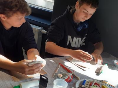 Dominik i Przemek ugniatają glinę na kafelki.