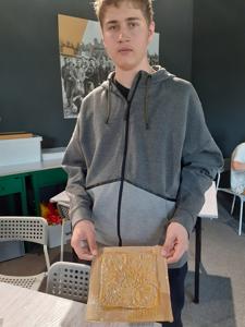 Alan wałkuje i modeluje glinę na kafelek.