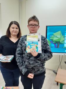 Filip w towarzystwie Pani Ani Z. pokazuje nagrody za zajęcie III miejsca.