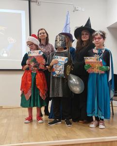 Nagrodzeni Madzia, Ania i Antek z nagrodami stoją na scenie.