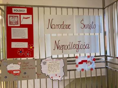 Zdjęcie gazetki ściennej, na której powieszone są informacje na temat Narodowego Święta Niepodległości: Godło Polski, Flaga Polski, napis, kontury Polski, plakaty uczniów klasy 0 oraz klasy III 