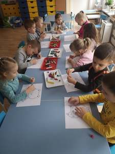 Dzieci wykonują małe kuleczki z plasteliny i wklejają je w małe kółeczka.