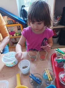 Ania starannie wsypuje kolorowy piasek