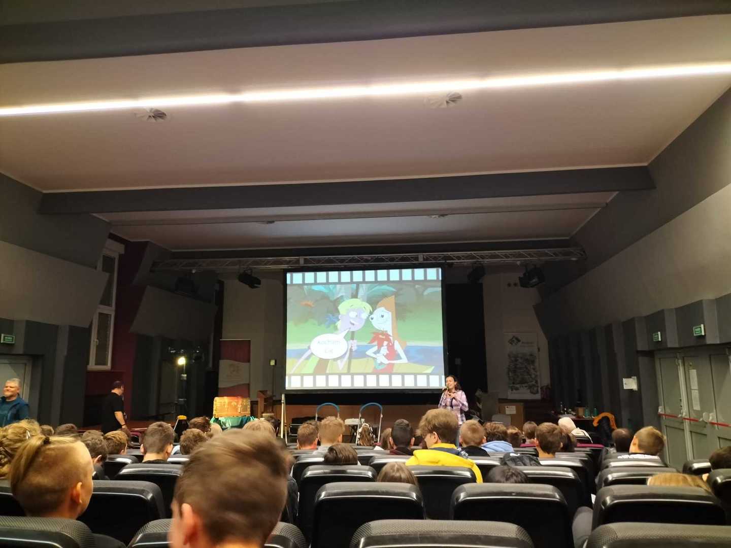 Sala wypełniona widzami. Na ekranie widać scenkę, za pomocą której omawiany jest temat zakochania.