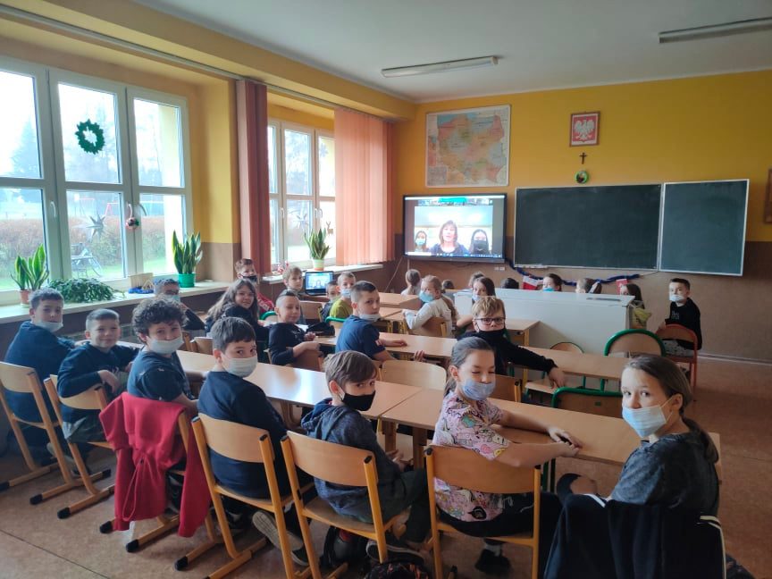 Uczniowie podczas warsztatów. W tle przestrzeń klasy, tablica multimedialna.
