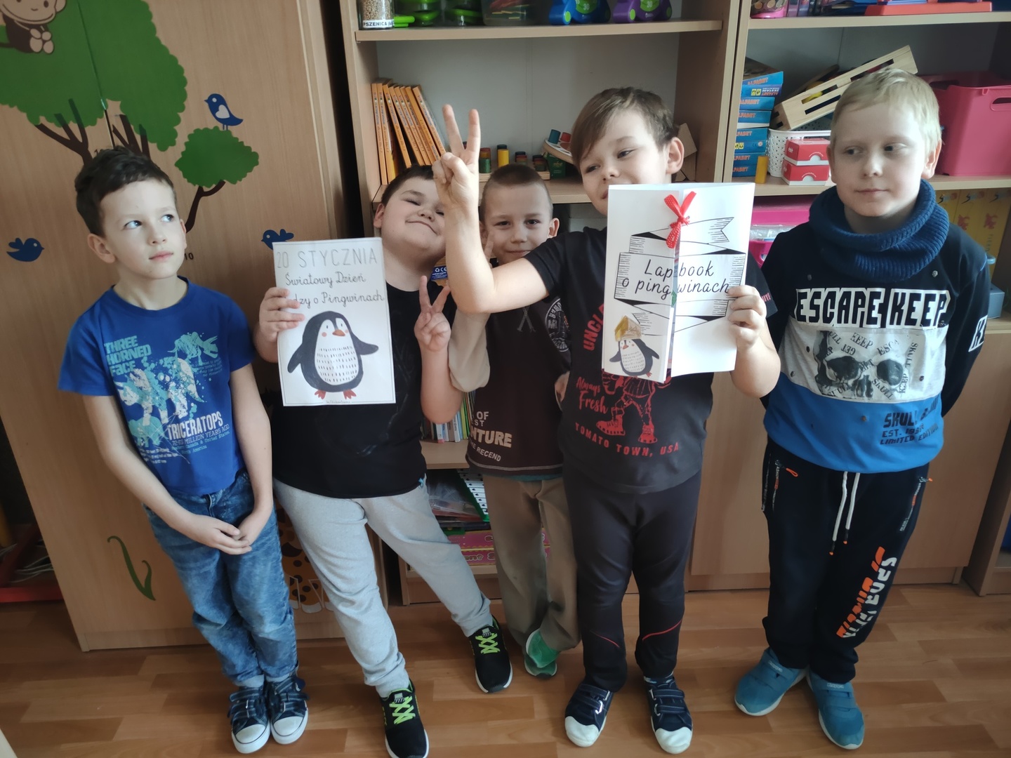 Uczniowie prezentujący efekty swojej pracy - lapbook. W tle szkolne szafy i regały.