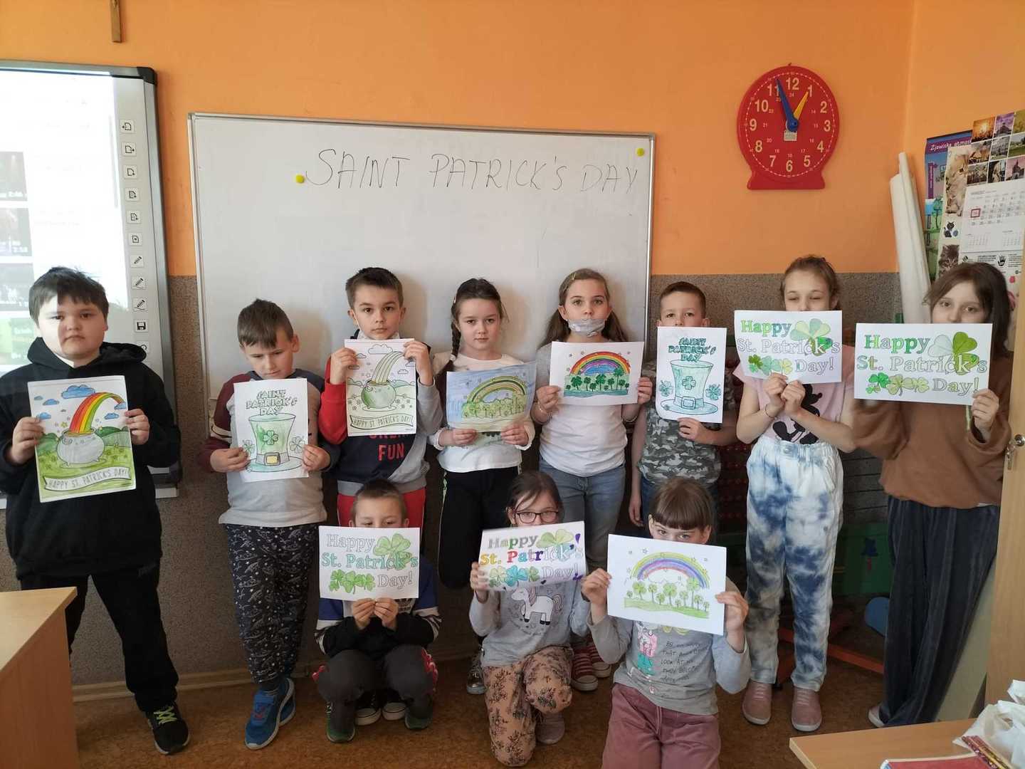 Uczniowie stoją z plakatami z okazji Dnia świętego Patryka.
