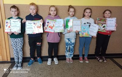 Zdjęcie przedstawia uczniów, którzy trzymają w ręce dyplomy wraz z nagrodami.